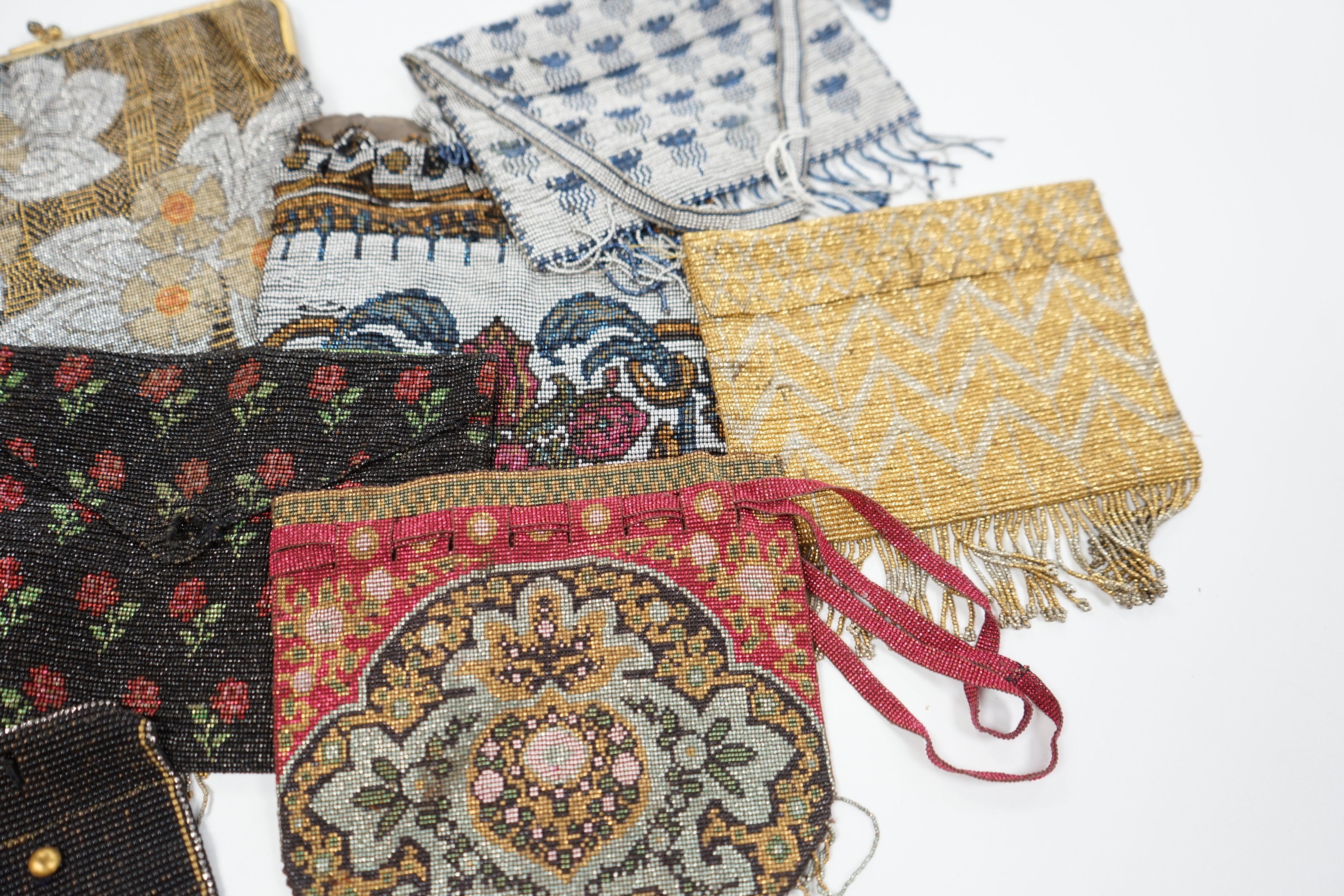 Seven late 19th century multicoloured and designed cut steel evening bags and a small coin purse (8)